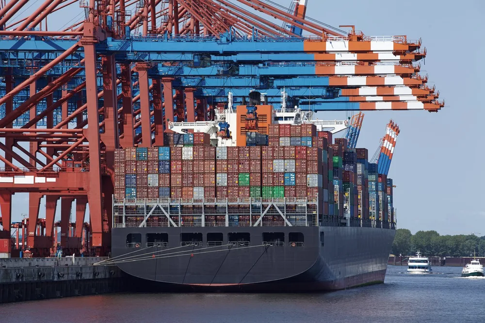 Container ship at the terminal, loading under the gantry cranes.