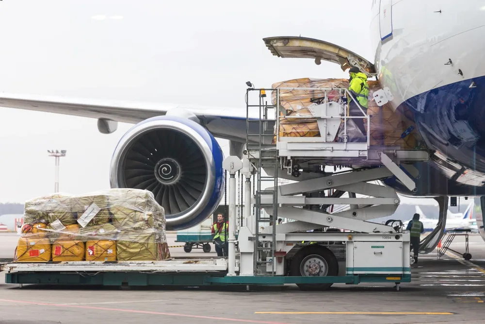 Air freight pallets being loaded into a cargo aircraft on a main-deck loader.